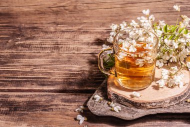 Akasya çiçeklerinden çay. Sağlıklı yaz vitamin içeceği, sert ışık, karanlık gölge. Tatlı bal, eski ahşap stantlar, kopyalama alanı