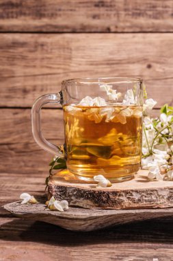 Akasya çiçeklerinden çay. Sağlıklı yaz vitamin içeceği, sert ışık, karanlık gölge. Tatlı bal, eski ahşap stantlar, kopyalama alanı