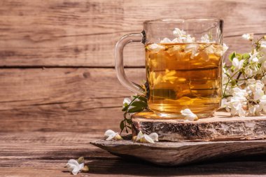 Akasya çiçeklerinden çay. Sağlıklı yaz vitamin içeceği, sert ışık, karanlık gölge. Tatlı bal, eski ahşap stantlar, kopyalama alanı