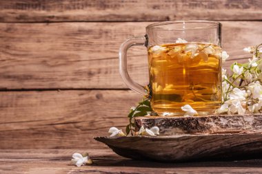 Akasya çiçeklerinden çay. Sağlıklı yaz vitamin içeceği, sert ışık, karanlık gölge. Tatlı bal, eski ahşap stantlar, kopyalama alanı