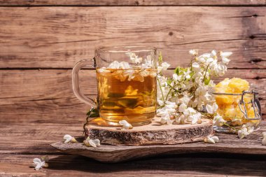 Akasya çiçeklerinden çay. Sağlıklı yaz vitamin içeceği, sert ışık, karanlık gölge. Tatlı bal, eski ahşap stantlar, kopyalama alanı