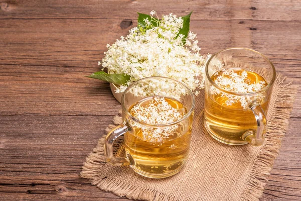 Mürver çiçeği çayı. Taze yaz içkisi, sağlıklı yaşam tarzı konsepti. Kumaş peçete, eski ahşap masa, kopyalama alanı