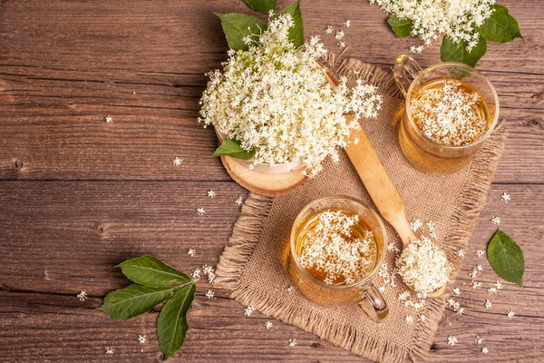 Mürver çiçeği çayı. Taze yaz içkisi, sağlıklı yaşam tarzı konsepti. Kumaş peçete, eski ahşap masa, üst manzara.