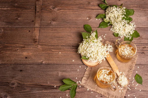 Mürver çiçeği çayı. Taze yaz içkisi, sağlıklı yaşam tarzı konsepti. Kumaş peçete, eski ahşap masa, üst manzara.