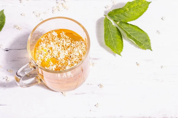 Mürver çiçeği çayı. Taze yaz içkisi, sağlıklı yaşam tarzı konsepti. Modaya uygun sert ışık, karanlık gölge. Eski beyaz tahta tahta arka plan, boşluğu kopyala