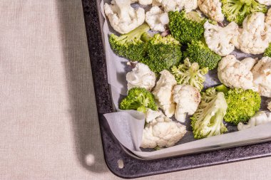 Karnabahar ve brokoli, pişirmeye hazır. Sağlıklı bir yaşam tarzı için yemek pişirme konsepti. Sert bir ışık, karanlık bir gölge, masada yemek tepsisi, üst manzara.