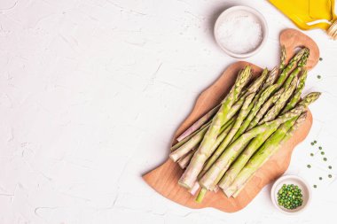 Tahta kesme tahtasında olgun kuşkonmaz. Sağlıklı yemek pişirmek için taze malzemeler hazır. Modern sert ışık, karanlık gölge. Beyaz macun arkaplan, üst görünüm