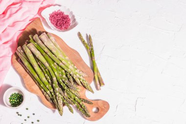 Tahta kesme tahtasında olgun kuşkonmaz. Sağlıklı yemek pişirmek için taze malzemeler hazır. Modern sert ışık, karanlık gölge. Beyaz macun arkaplan, üst görünüm
