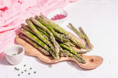 Tahta kesme tahtasında olgun kuşkonmaz. Sağlıklı yemek pişirmek için taze malzemeler hazır. Modern sert ışık, karanlık gölge. Beyaz macun arkaplanı, kopyalama alanı