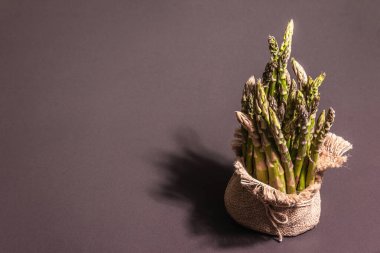 Çuval bezinde bir sürü kuşkonmaz. Sağlıklı yiyecekler için taze malzeme, siyah taş pişirme arka planı, kopyalama alanı
