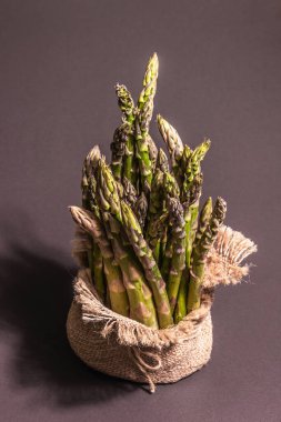 Çuval bezinde bir sürü kuşkonmaz. Sağlıklı yiyecekler için taze malzeme, siyah taş pişirme arka planı, kopyalama alanı