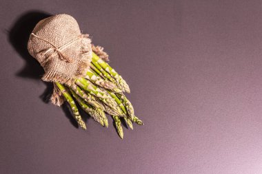 Çuval bezinde bir sürü kuşkonmaz. Sağlıklı yemek için taze malzeme, siyah taş pişirme arka planı, üst görünüm.