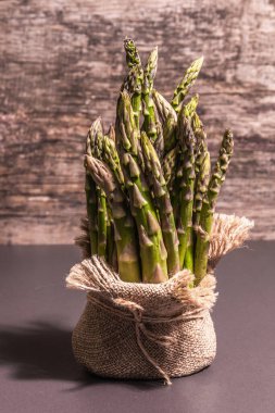 Çuval bezinde bir sürü kuşkonmaz. Sağlıklı yiyecekler için taze malzeme, siyah taş pişirme arka planı, kopyalama alanı