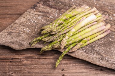 Olgun kuşkonmaz pişirmeye hazır. Klasik ahşap tribünler, sert ışık, karanlık gölge. Eski tahta arkaplanı, kopyala