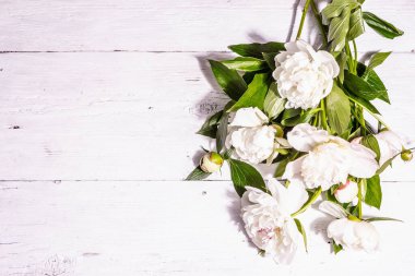 Bir buket taze beyaz şakayık. Yaz narin çiçekleri, romantik hediye konsepti. Çiçek aranjmanı, modaya uygun sert ışık, karanlık gölgeler. Beyaz eski tahtalar arkaplan, üst görünüm