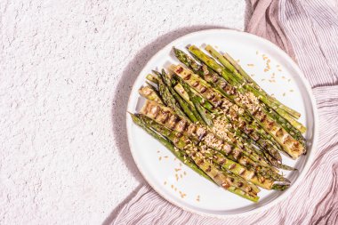 Olgun ızgara kuşkonmaz. Sos, altın keten tohumu, sağlıklı ve sağlıklı gıda konsepti. Modern sert ışık, karanlık gölge. Hafif macun arkaplanı, üst görünüm