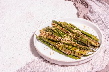 Olgun ızgara kuşkonmaz. Sos, altın keten tohumu, sağlıklı ve sağlıklı gıda konsepti. Modern sert ışık, karanlık gölge. Hafif macun arkaplanı, kopyalama alanı