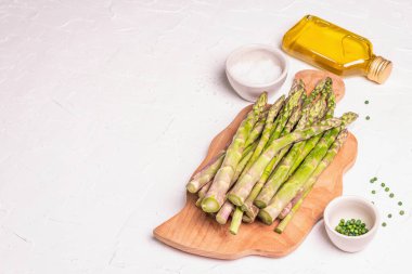 Tahta kesme tahtasında olgun kuşkonmaz. Sağlıklı yemek pişirmek için taze malzemeler hazır. Modern sert ışık, karanlık gölge. Beyaz macun arkaplanı, kopyalama alanı