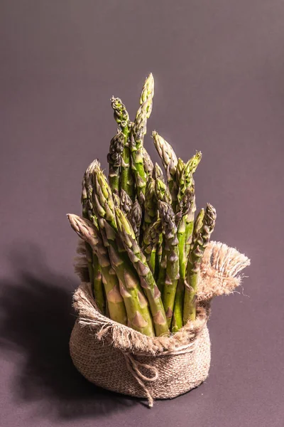 Çuval bezinde bir sürü kuşkonmaz. Sağlıklı yiyecekler için taze malzeme, siyah taş pişirme arka planı, kopyalama alanı