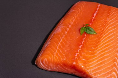 Taze çiğ somon ya da alabalık filetosu. Siyah taş arka planda. Sağlıklı yiyecekler için kullanışlı bir malzeme, Omega 3 kaynağı. Modern bir sert ışık, karanlık gölge, mutfak kağıdı, kopyalama alanı