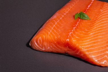 Taze çiğ somon ya da alabalık filetosu. Siyah taş arka planda. Sağlıklı yiyecekler için kullanışlı bir malzeme, Omega 3 kaynağı. Modern bir sert ışık, karanlık gölge, mutfak kağıdı, kopyalama alanı