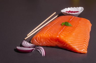 Taze çiğ somon ya da alabalık filetosu. Siyah taş arka planda. Sağlıklı yiyecekler için kullanışlı bir malzeme, Omega 3 kaynağı. Modern bir sert ışık, karanlık gölge, mutfak kağıdı, kopyalama alanı