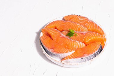 Taze çiğ somon ya da balık fileto bifteği. Minimalist tasarım, modern sert ışık, karanlık gölge. Sağlıklı deniz ürünleri pişirmek için soğutulmuş malzemeler. Beyaz macun mutfak arkaplanı, kopyalama alanı