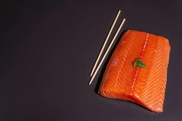 黒石の背景に新鮮な生鮭やマスの魚の切り身 健康食品 オメガ3のソースのための有用な成分 現代的なハードライト 暗い影 トップビュー — ストック写真