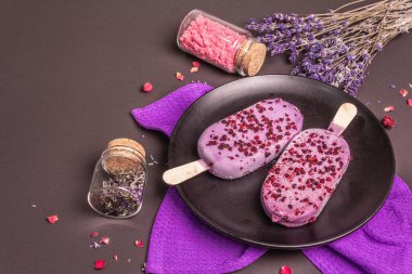 Lavanta aromalı dondurma. Çiçek buketi, pembe şeker, gül yaprakları. Siyah taş arkaplan, boşluğu kopyala