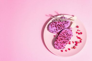Lavanta ve gül yapraklı dondurma, tatlı soğuk tatlı. Modaya uygun sert ışık, karanlık gölge. Pembe pastel arkaplan, üst görünüm