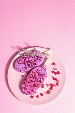 Lavanta ve gül yapraklı dondurma, tatlı soğuk tatlı. Modaya uygun sert ışık, karanlık gölge. Pembe pastel arkaplan, üst görünüm
