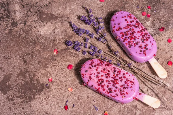 Lavender ice cream. Flower bouquet, pink rose petals. Trendy hard light, dark shadow. Marble stone background, top view, flat lay