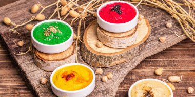 Nohut humus arkaplanı. Farklı sebze ve baharatlarla çeşnili. Antika ahşap masa, modern sert ışık, karanlık gölge, bayrak