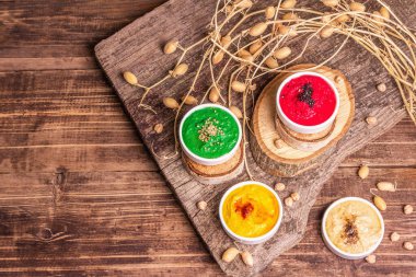 Nohut humus arkaplanı. Farklı sebze ve baharatlarla çeşnili. Eski ahşap masa, modern sert ışık, karanlık gölge, üst manzara.