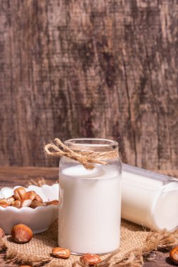 Ev yapımı vejetaryen kavrulmuş fındık sütü. Süt içermeyen sağlıklı ürün, eski ahşap masa. Modern sert ışık, karanlık gölge, boşluğu kopyala