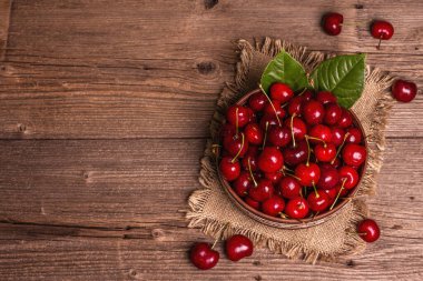 Bir kase dolusu su damlacıklarıyla taze kirazlar. Koyu kırsal ahşap arka plan, üst görünüm