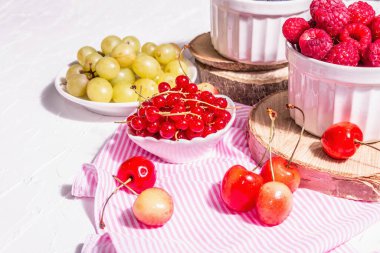 Çeşit çeşit olgun böğürtlen kaseleri. Taze ahududu, yabanmersini, üzüm, tatlı kiraz ve kırmızı frenk üzümü. Beyaz alçı arkaplan, metin için yer