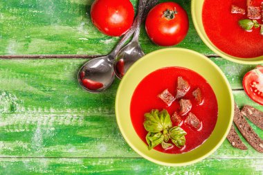 Fesleğenli domates çorbası. Olgun sebzeler, taze yeşiller, mis kokulu baharatlar. Tahta masa.