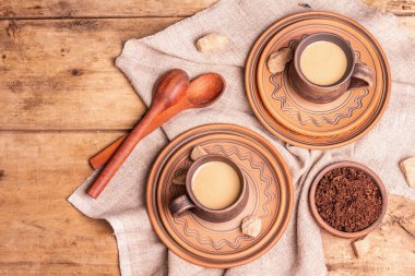 Sıcak bir ev tarzında afromatik kahve. Seramik kupalar, sıcak içecek, ahşap masa. Günaydın, iyi ruh hali, güzel manzara.