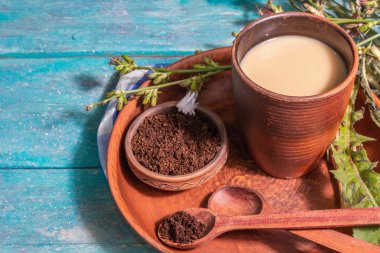 Taze çiçekler ve pudra ile doğal hindiba kahvesi. Seramik bardakta kafeinsiz içecek. Alternatif kahve, kafein. Turkuaz ahşap arka plan, metin için yer