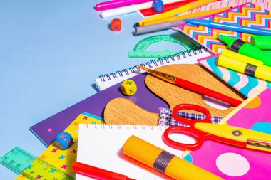 Mavi arka planda kırtasiye aksesuarı. Okul malzemeleri, kalemler, boyalar, makas ve renkli defterler. Eğitim ve serbest çalışma kavramı, kopyalama alanı