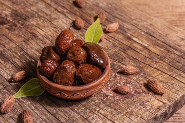 Seramik kasede güneşte kurutulmuş zeytin. Geleneksel Yunan aperatifleri, kuru tohumlar, eski ahşap masa. Mutfak arkaplanı, kopyalama alanı