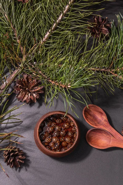 Tatlı kozalak reçeli. Geleneksel Sibirya tatlıları, taze yeşil dallar. Modaya uygun sert ışık, karanlık gölge. Siyah taş arkaplan, üst görünüm