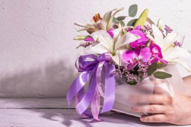 Adamın elleri buketi tutuyor. Beyaz arka planda güzel, taze bir çiçek. Düğünler, doğum günleri, Anneler Günü, Sevgililer Günü ya da 8 Mart kutlamaları. Tebrik kartı, metin için bir yer, düz uzanma