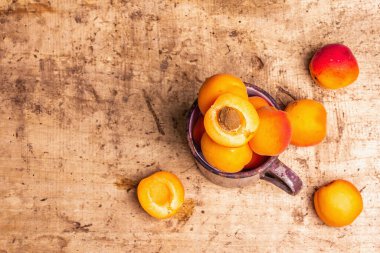 Eski bir demir kupada olgun kayısılar. Tatlı meyveler, eski ahşap masa, üst manzara.