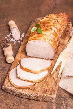 Taş zeminde ev yapımı domuz filetosu. Tam kavrulmuş parça, baharatlı dilimler, düz yatak, yakın çekim.