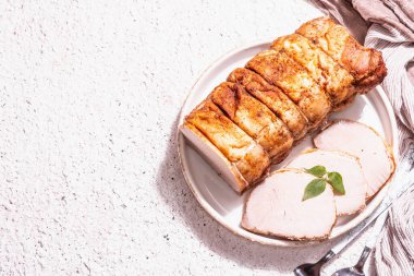 Seramik tezgahta çatal bıçaklı fırında domuz filetosu. Modaya uygun sert ışık, koyu gölge, beyaz macun arkaplan, üst görünüm