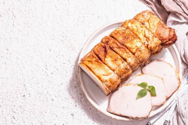 Seramik tezgahta çatal bıçaklı fırında domuz filetosu. Modaya uygun sert ışık, koyu gölge, beyaz macun arkaplan, üst görünüm