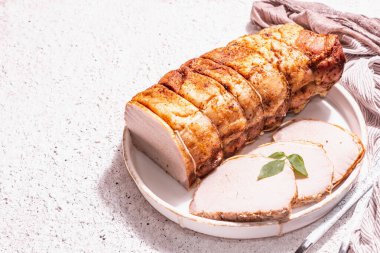 Seramik tezgahta çatal bıçaklı fırında domuz filetosu. Modaya uygun bir sert ışık, koyu gölge, beyaz macun arkaplanı, metin için yer