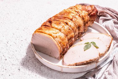 Seramik tezgahta çatal bıçaklı fırında domuz filetosu. Modaya uygun bir sert ışık, koyu gölge, beyaz macun arkaplanı, metin için yer